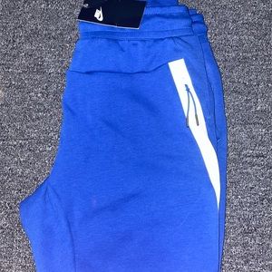 Blue Nike tech pants.